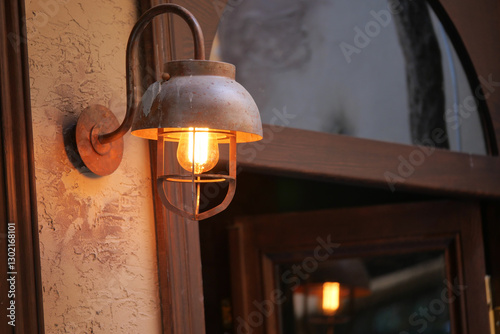 Rustic light fixture illuminating an entrance at dusk