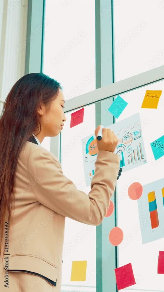 Business people work on project planning board in office and having conversation with coworker friend to analyze project development . They use sticky notes posted on glass wall to make it organized . Business people work on project planning board in office and having conversation with coworker friend to analyze project development . They use sticky notes posted on glass wall to make it organized .