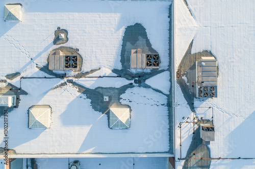 A roof covered in snow, with a few vents and chimneys visible
