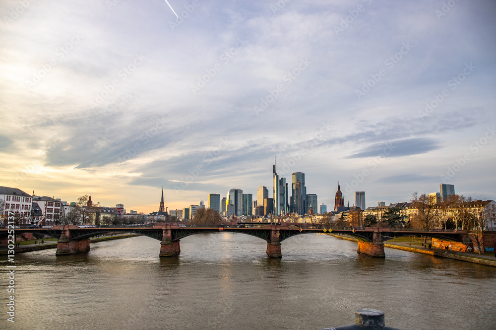 View from a Main Bridge of a skyline in the financial district in the background as the sun sets. Twilight in Frankfurt am Main, Hesse Germany View from a Main Bridge of a skyline in the financial district in the background as the sun sets. Twilight in Frankfurt am Main, Hesse Germany