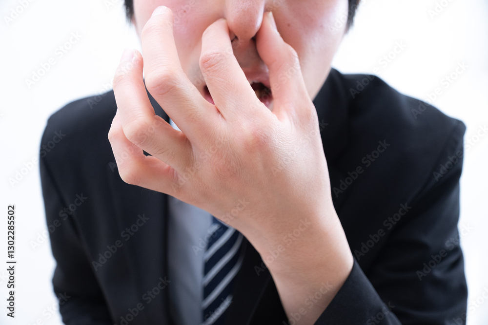 鼻を摘んで臭さに耐える男性
