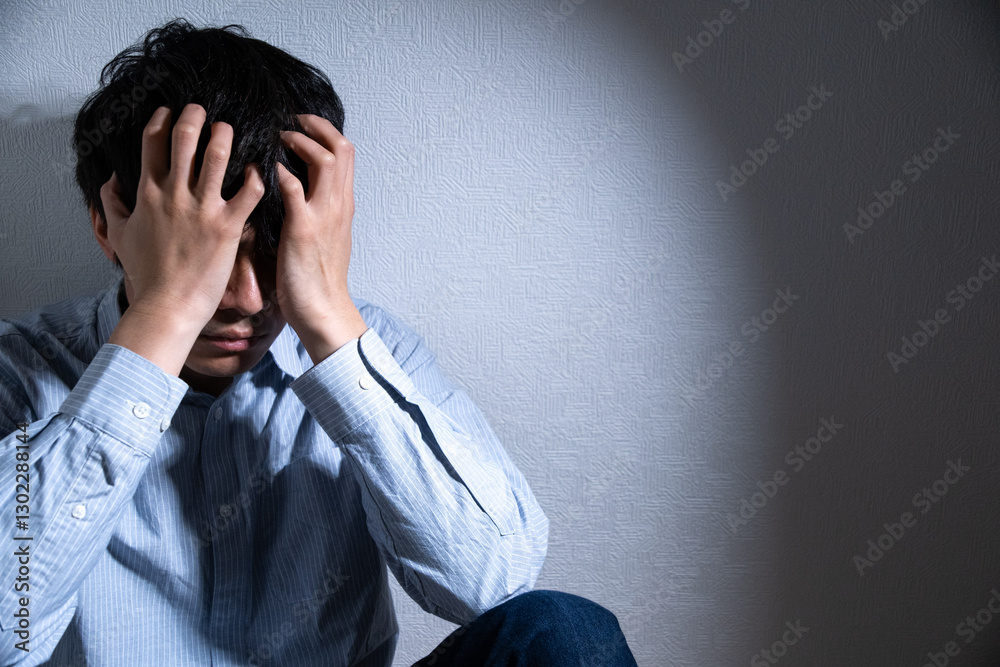 頭を抱えて落ち込む男性とスポットライト