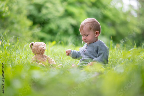 Baby mit Teddybär im Grünen
