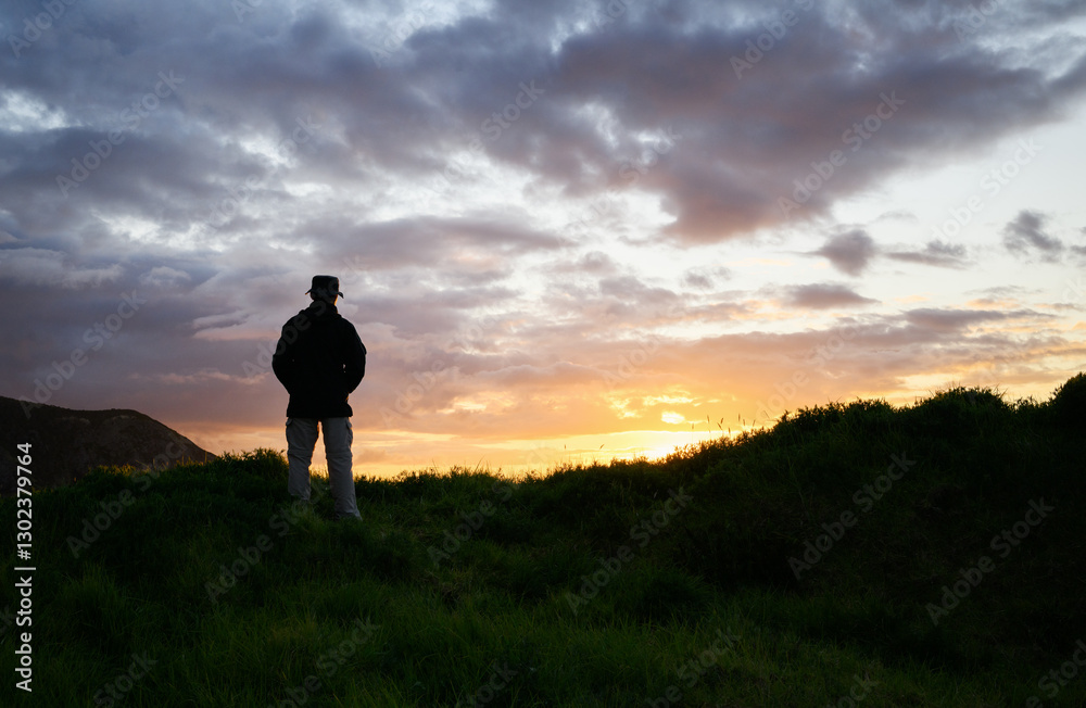 Man in silhouette watching sunset at Cape Brett Peninsula. Bay of Islands. New Zealand.