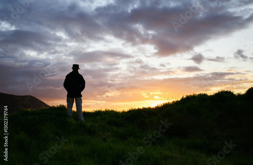 Obraz na płótnie Man in silhouette watching sunset at Cape Brett Peninsula. Bay of Islands. New Zealand. w salonie