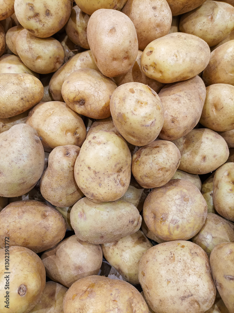 Top-down view of a neatly stacked display of fresh potatoes. Earthy brown potatoes arranged in an organized pattern, highlighting their natural texture and rustic appearance. Top-down view of a neatly stacked display of fresh potatoes. Earthy brown potatoes arranged in an organized pattern, highlighting their natural texture and rustic appearance.