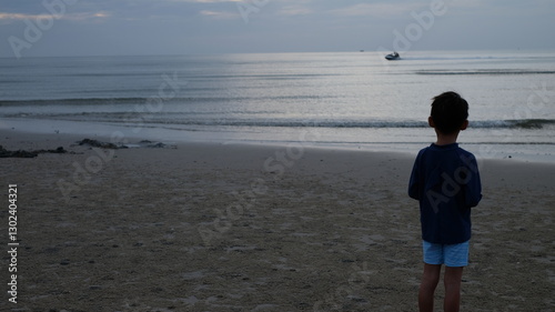 A serene evening scene captures a child gazing out at the vast expanse of the sea.