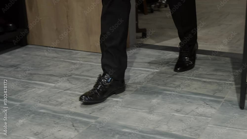 Low section of man wearing new shiny shoes walking on floor. Male customer testing formal footwear. He is shopping at fashion shop. Low section of man wearing new shiny shoes walking on floor. Male customer testing formal footwear. He is shopping at fashion shop.