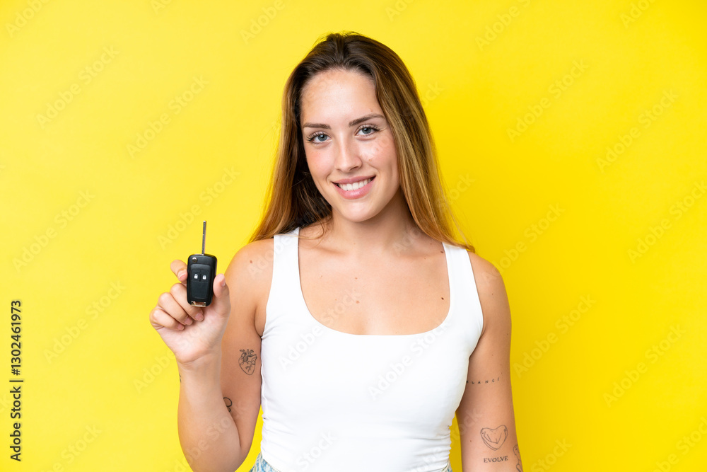 Young caucasian woman holding car keys isolated on yellow background smiling a lot Young caucasian woman holding car keys isolated on yellow background smiling a lot