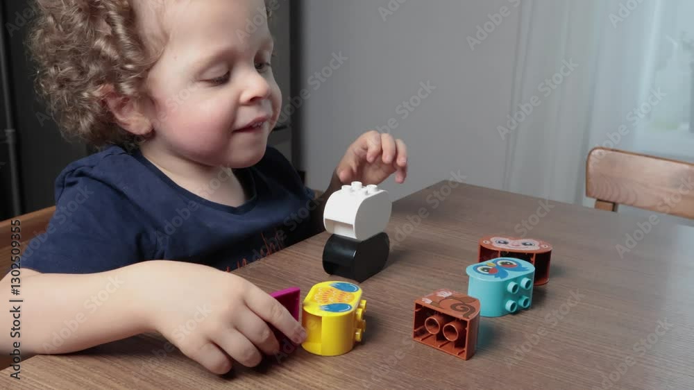 Happy little boy playing with plastic constructor at home on table and smiling. Children and educational games. Animals of Africa.