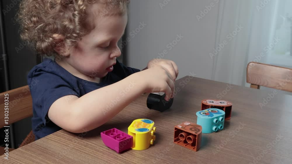 Little boy plays with plastic constructor at home on table. Children and educational games. Animals and nature. Little boy plays with plastic constructor at home on table. Children and educational games. Animals and nature.