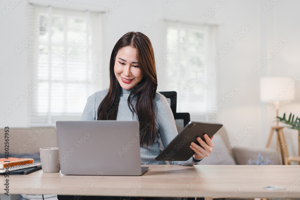 Asian businesswoman smiling while using smartphone at desk with notebook, coffee mug, and indoor plants. Asian businesswoman smiling while using smartphone at desk with notebook, coffee mug, and indoor plants.