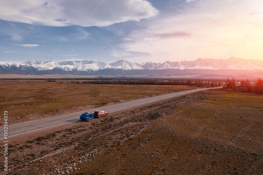 Fototapeta premium Camper trailer journey through scenic Altay mountain landscape at sunset