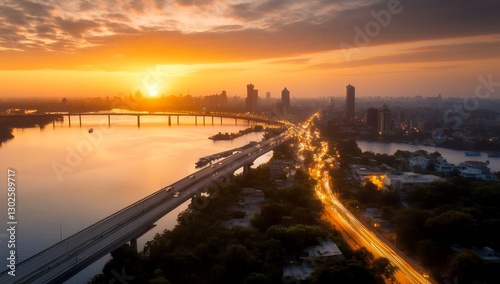 Golden sunrise illuminates a city skyline, reflecting on a river with a bridge and highway traffic