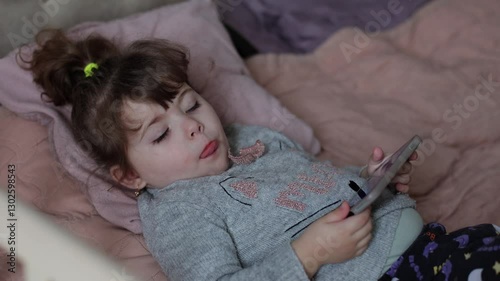 A child in a smartphone. Addiction to gadgets, looking at the phone. Fun in the device, a little girl is watching a video on the Internet