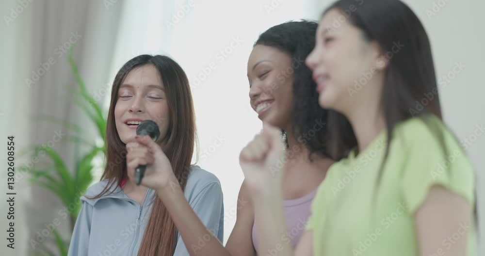 A group of three young multicultural friends singing and enjoying a karaoke session indoors. They are laughing and having fun, creating a joyful and energetic atmosphere.
A group of three young multicultural friends singing and enjoying a karaoke session indoors. They are laughing and having fun, creating a joyful and energetic atmosphere.