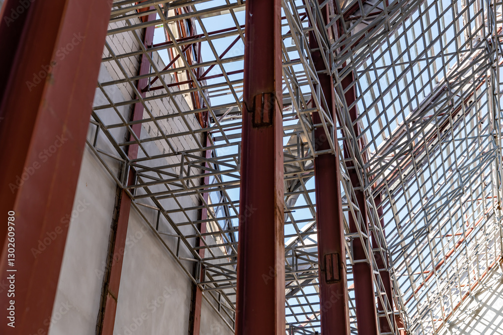 Obraz premium Uprisen angle photo shot of the huge steel roof frame structure detail under construction at the work site.