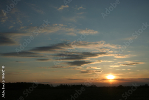 Fotografía The setting sun through the clouds over the field in the silence of the evening