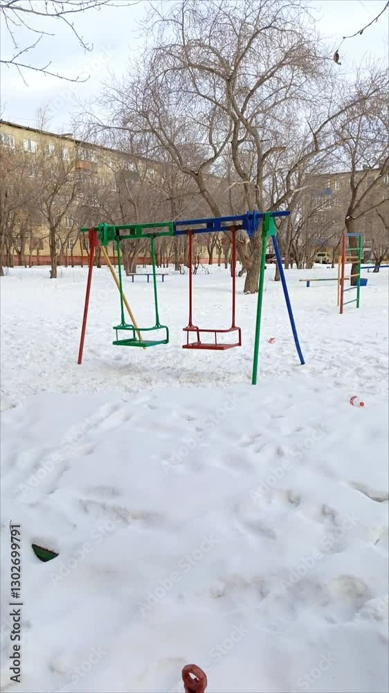 An old outdoor swing on a children's playground in winter. Metal swing in the snow. An old outdoor swing on a children's playground in winter. Metal swing in the snow.
