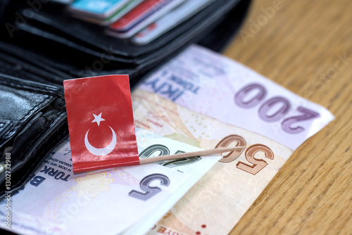 Fototapeta Naklejka Na Ścianę i Meble -  Turkish flag laying on Turkish lira banknotes, wallet in the background, concept for economy or business status in Turkey.