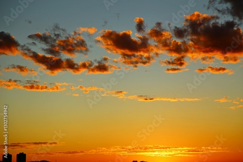 
Beautiful clouds in vibrant colors. Dawn with reddish clouds in the sky. Sun rising over the horizon, yellow reflections in the sky.