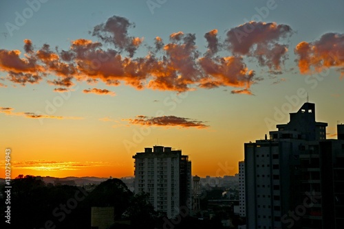 city buildings on silhouettes, urban scape.
Dawn with reddish clouds in the sky. Sun rising over the horizon, yellow reflections in the sky.