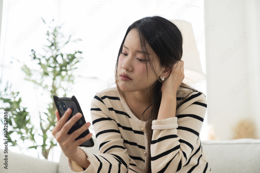 Woman, mobile phone, young asian woman using tablet during sitting on sofa in living room at home Woman, mobile phone, young asian woman using tablet during sitting on sofa in living room at home