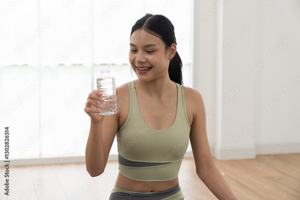 Woman, drinking water. Woman drinking water from bottle during sitting on yoga mat in home. Working out, Exercise, Wearing sportswear, Yoga at home Woman, drinking water. Woman drinking water from bottle during sitting on yoga mat in home. Working out, Exercise, Wearing sportswear, Yoga at home