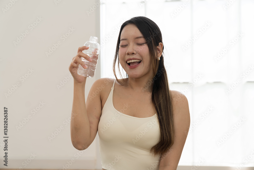 Woman, drinking water. Woman drinking water from bottle during sitting on yoga mat in home. Working out, Exercise, Wearing sportswear, Yoga at home Woman, drinking water. Woman drinking water from bottle during sitting on yoga mat in home. Working out, Exercise, Wearing sportswear, Yoga at home