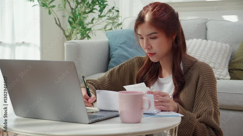 Young asian woman calculates bills and cost for planning finance, woman looking expense with burden or investment and writing on paperwork, statement banking and debt for loan, business and financial. Young asian woman calculates bills and cost for planning finance, woman looking expense with burden or investment and writing on paperwork, statement banking and debt for loan, business and financial.