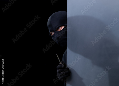 Studio shot of a stealthy thief breaking into a room and carefully looking around isolated on black background