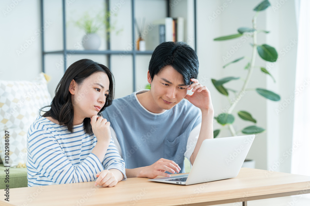 パソコンで悩む若い夫婦 パソコンで悩む若い夫婦