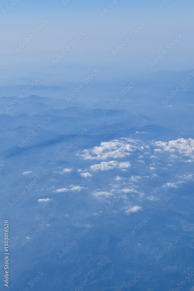 The view of the stunning landscape with mountains and clouds from the airplane window. Aerial view of the natural scene, mountain range. Travel and landscape scene. Travel and nature concept. The view of the stunning landscape with mountains and clouds from the airplane window. Aerial view of the natural scene, mountain range. Travel and landscape scene. Travel and nature concept.