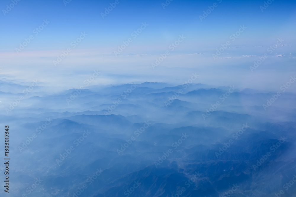 The view of the stunning landscape with mountains and clouds from the airplane window. Aerial view of the natural scene, mountain range. Travel and landscape scene. Travel and nature concept. The view of the stunning landscape with mountains and clouds from the airplane window. Aerial view of the natural scene, mountain range. Travel and landscape scene. Travel and nature concept.