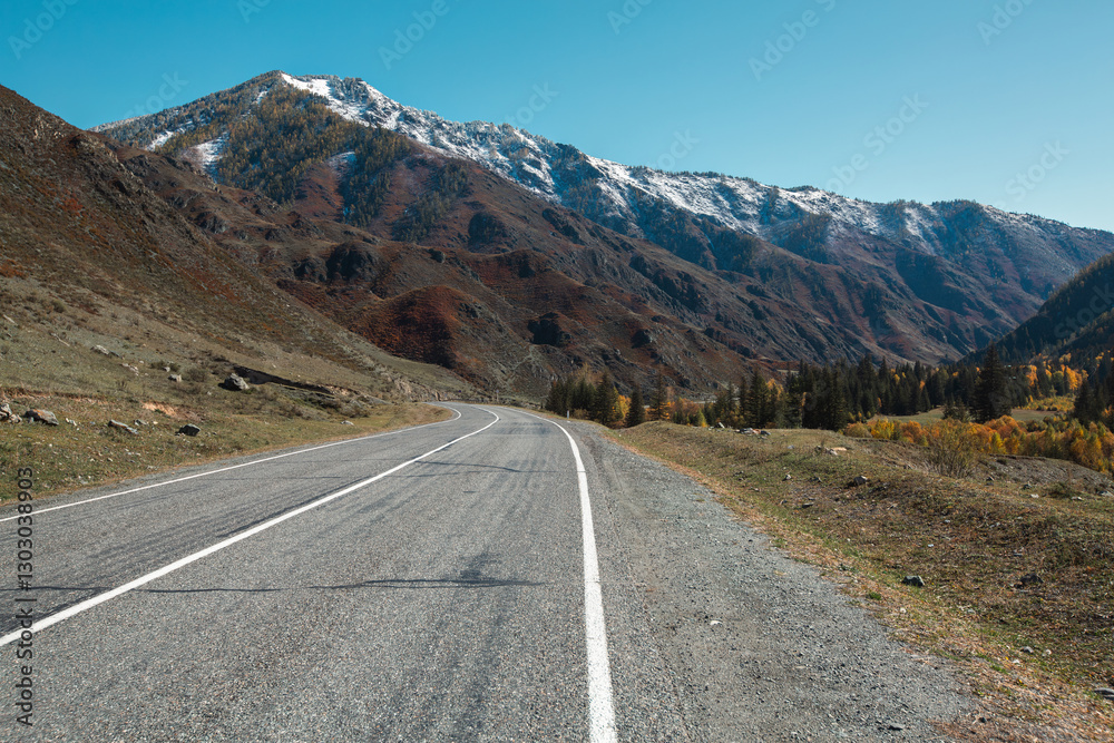 A mountain road winding through the peaks of the Altai Republic, surrounded by breathtaking landscapes.