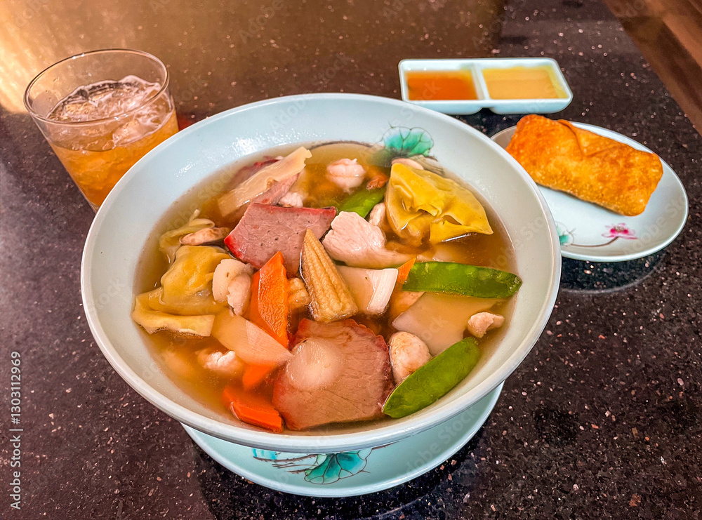 A delicious bowl of wonton soup filled with dumplings, BBQ pork, chicken, shrimp, and fresh veggies. Served with an egg roll, dipping sauces, and a refreshing iced drink.