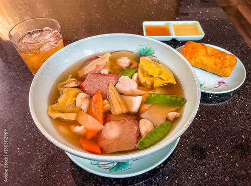 A delicious bowl of wonton soup filled with dumplings, BBQ pork, chicken, shrimp, and fresh veggies. Served with an egg roll, dipping sauces, and a refreshing iced drink.