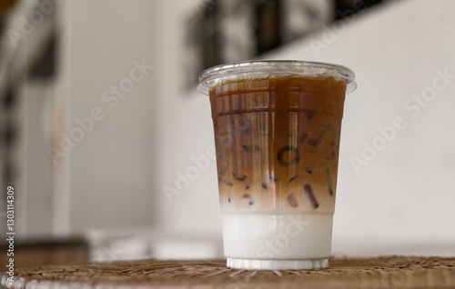 Iced coffee mixed milk, latte coffee in plastic cup on table with blurred background in cafe