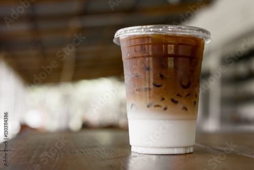 Iced coffee mixed milk, latte coffee in plastic cup on table with blurred background in cafe
