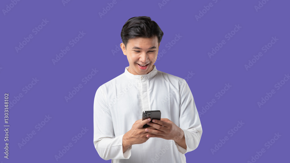 Cheerful young Asian Muslim man making a video call on mobile phone, isolated on white background.
Ramadan and Eid celebrations on purple background Cheerful young Asian Muslim man making a video call on mobile phone, isolated on white background.
Ramadan and Eid celebrations on purple background