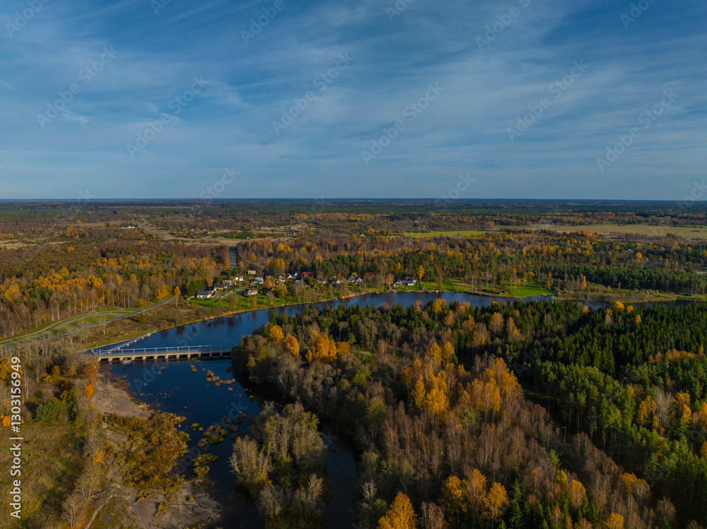 Naklejka premium Aerial photo of beautiful autumn landscape. Jagala (Estonian Jägala) river meandering through a dense forest of mixed trees - in gold, orange and green colors. Small bridge crosses the river. 