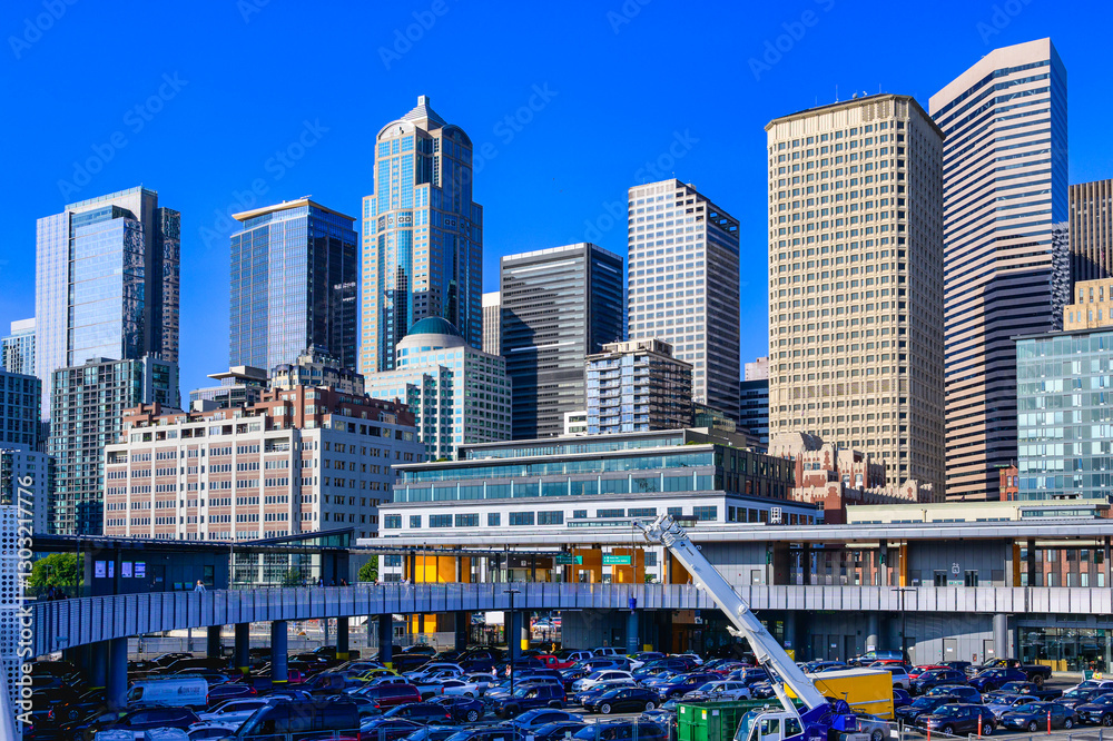 Fototapeta premium 2024-08-15 VIEW OF THE DOWNTOWN SKYSCRAPERS ALONG THE WATERFRONT IN SEATTLE WASHINGTON FROM THE COLEMAN DOCK WITH SEVERAL BUILDINGS AND A NICE BLUE SKY 