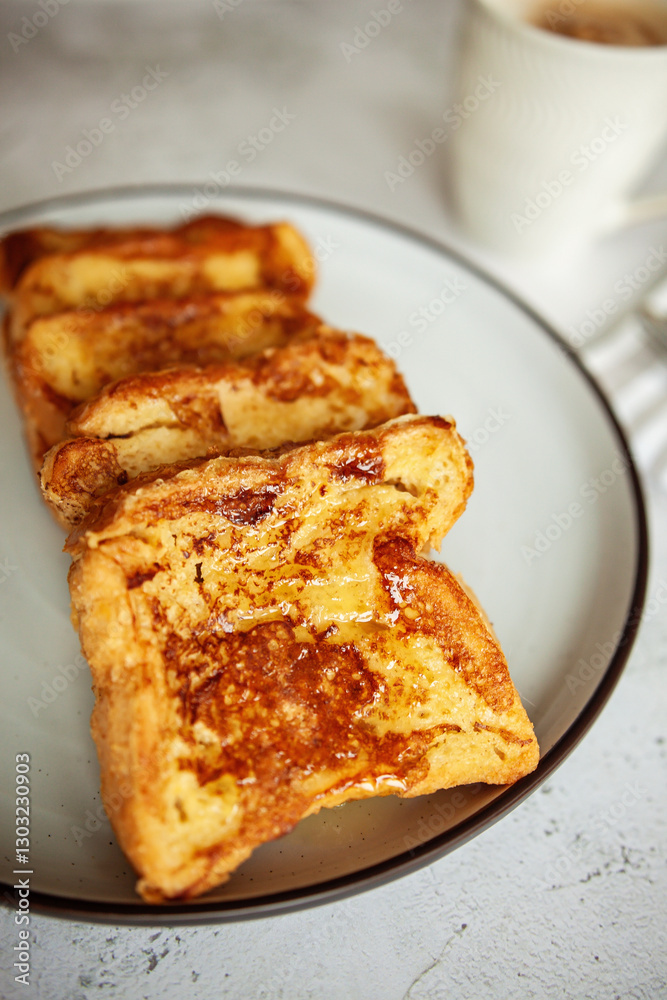 French toast with honey, traditional sweet homemade breakfast of bread soaked in eggs and milk, served on a white plate and shot in bright morning light French toast with honey, traditional sweet homemade breakfast of bread soaked in eggs and milk, served on a white plate and shot in bright morning light
