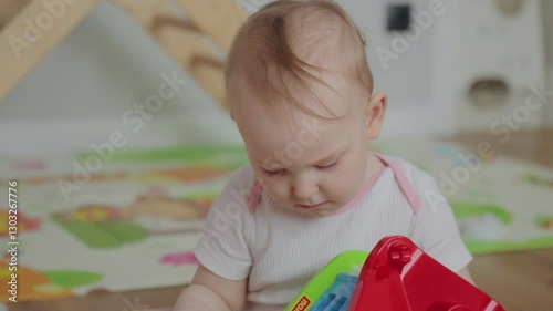A joyful infant sits on a soft mat, focused on colorful toys scattered around.