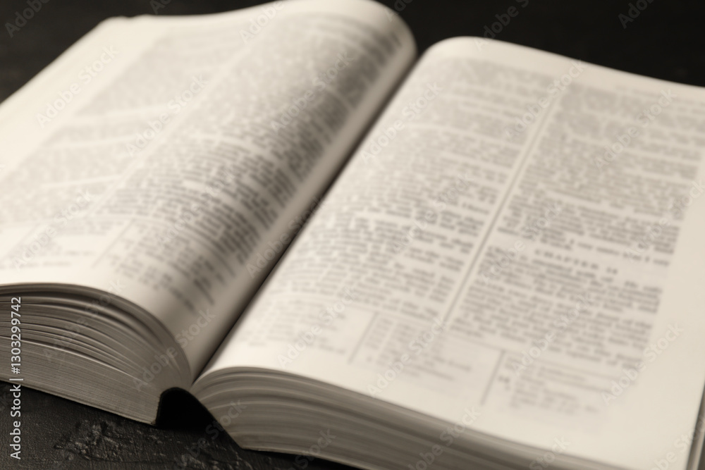 Open Holy Bible in English language on black table, closeup Open Holy Bible in English language on black table, closeup