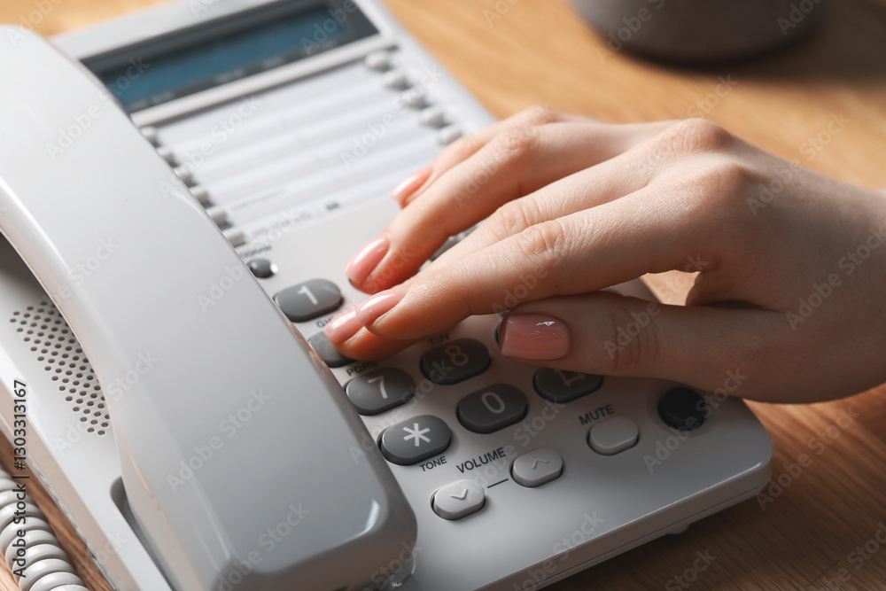 Woman dialing number on telephone at wooden table, closeup Woman dialing number on telephone at wooden table, closeup