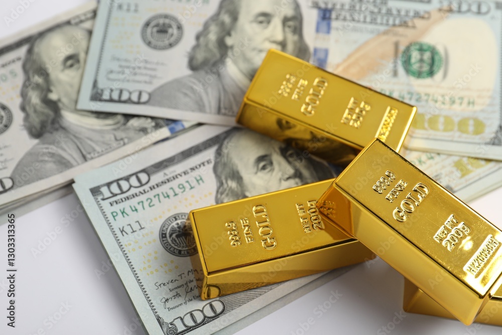 Shiny gold bars and dollar banknotes on white background, closeup