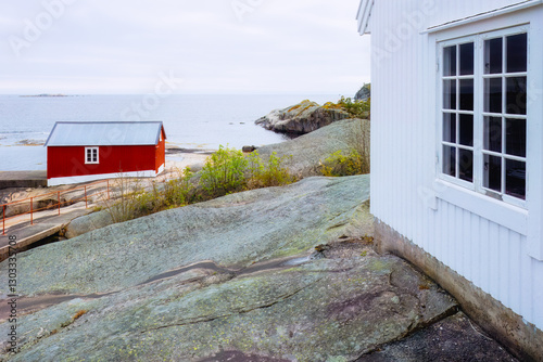 Bild auf Leinwand White wooden lighthouse wall over the sea and classic red boathouse nearby