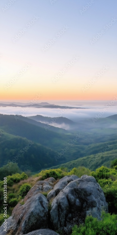 Fototapeta premium A mountain range with a foggy sky and a beautiful sunset. The mountains are covered in lush green trees and the sky is a mix of orange and blue hues. The scene is serene and peaceful