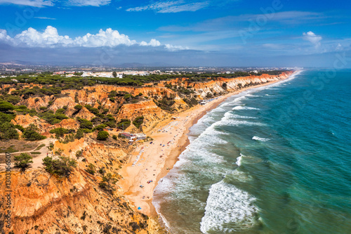 Aerial seascape and coastline cliffs of Praia do Barranco das Belharucas beach, in Algarve region in South Portugal. Praia do Barranco das Belharucas beach, Albufeira, Algarve, Portugal.